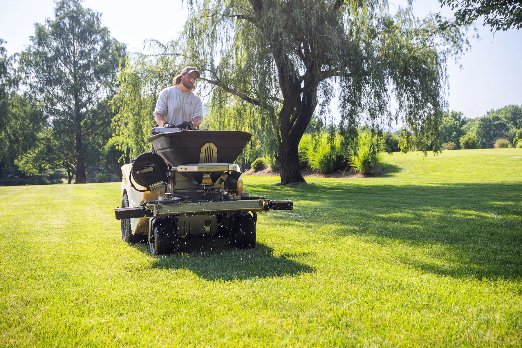 Lawn care technician applying granular fertilizer with ride-on equipment