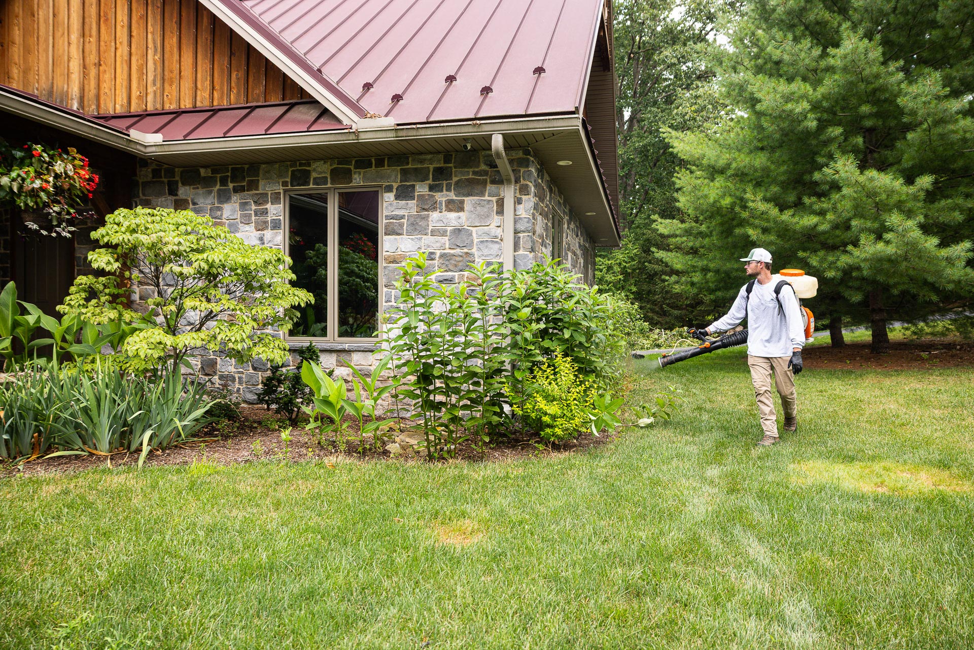 Technician applying mosquito control fog spray to shrubs and beds
