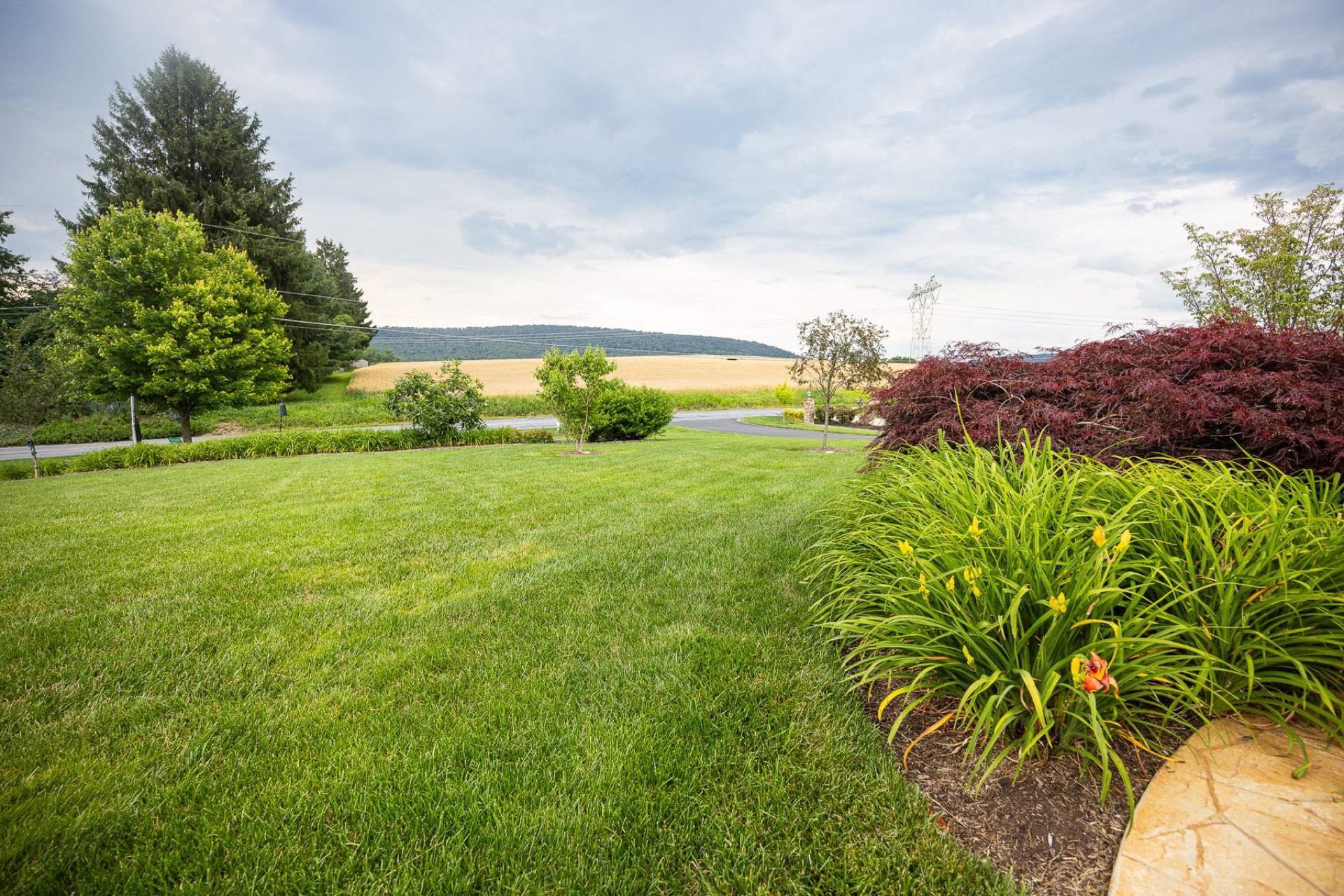 Manicured lawn meeting planted beds and a wooded property edge in South Central PA