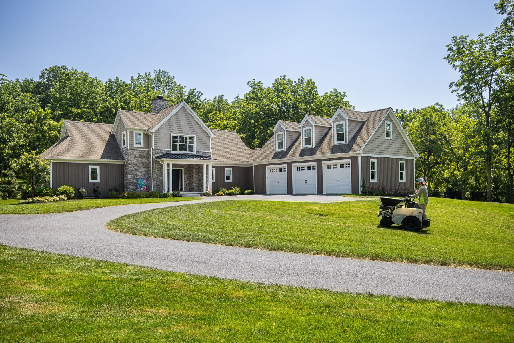lawn care technician applying a fertilizer and pre-emergent treatment for the spring