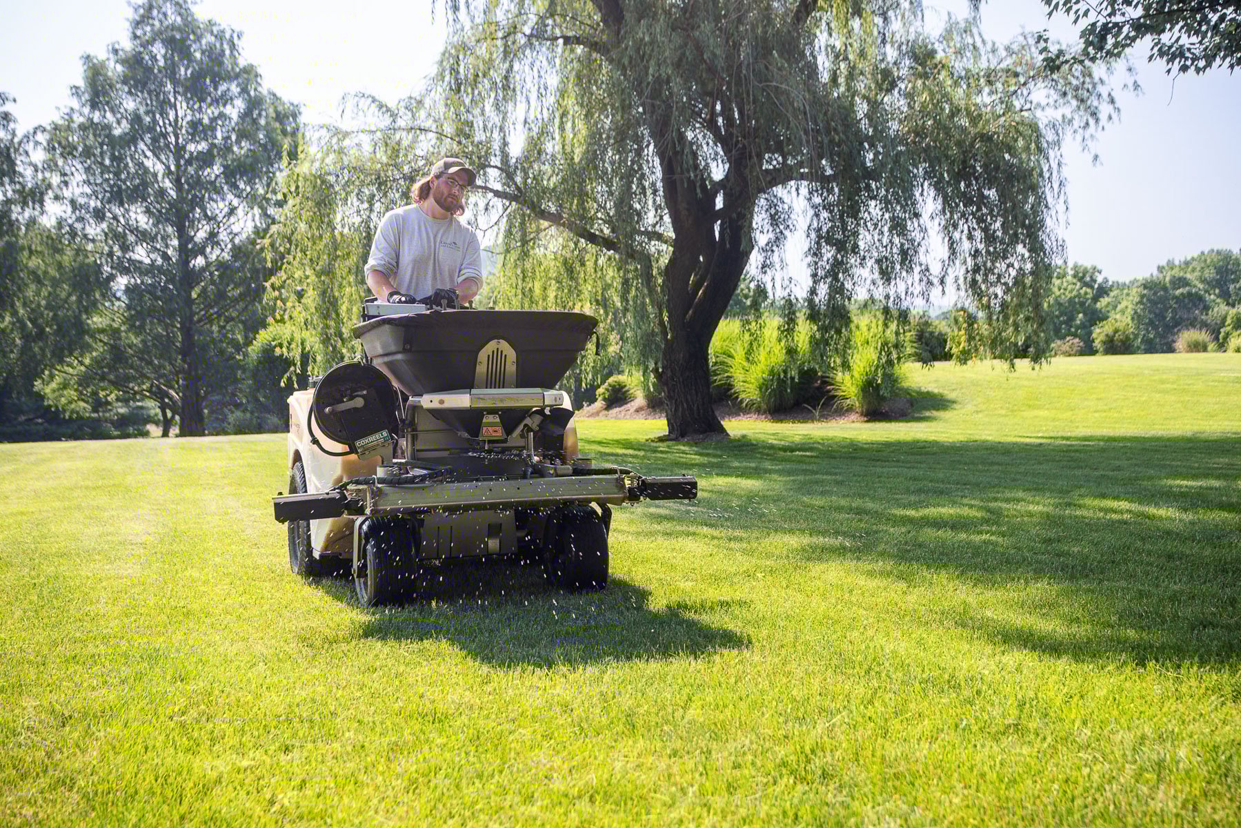 lawn care tech applying granular fertilizer