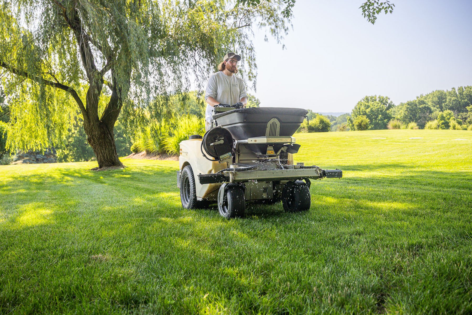 lawn care technician spreading granular fertilizer