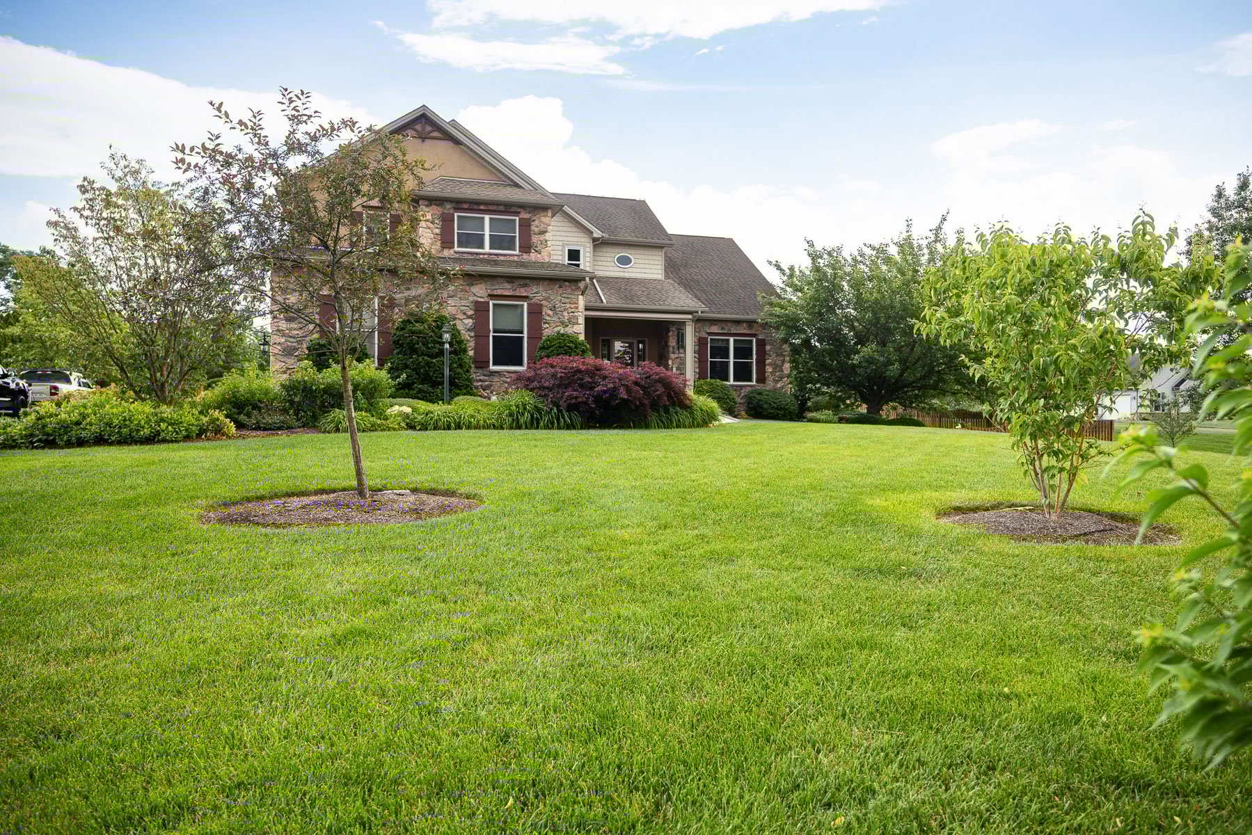 nice green grass lawn flower planting bed trees gravel tree rings mulch home